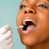 Person putting DNA test swab into woman's mouth, close up, studio shot