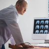 Male doctor looking at desktop screens of MRI x-rays in radiology lab