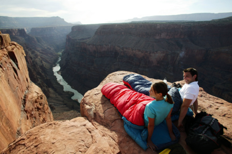 Couple in sleeping bags on canyon cliff