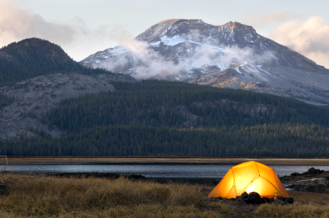 USA, Oregon, Bend, illuminated tent by lake in mountains