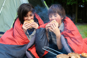Young boy and girl camping in forest, Eating burgers from the barbeque